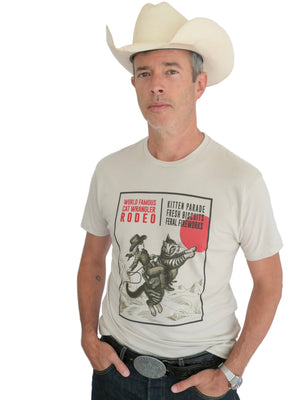 Man wearing a cowboy hat and a light t-shirt with a cat wrangler design