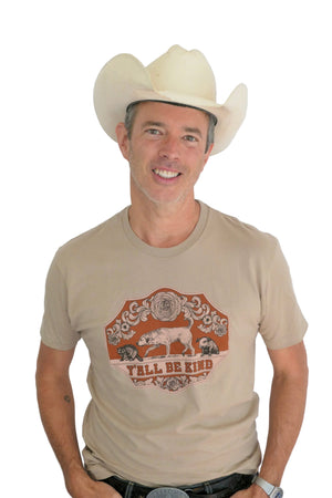 Man wearing a tan t-shirt that says Y'all Be Kind with an animal western design
