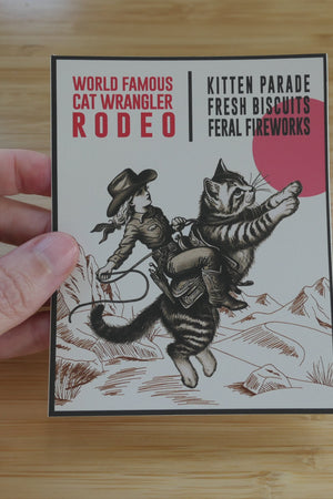 Hand holding a Cat Wrangler Rodeo sticker