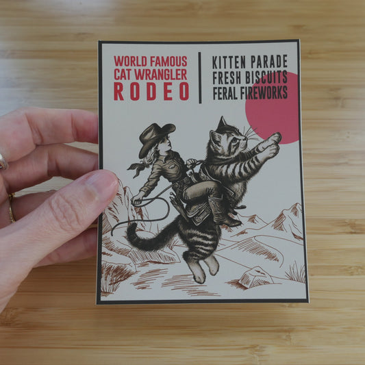 Hand holding a Cat Wrangler Rodeo sticker