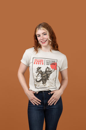 Woman wearing a Cat Wrangler Rodeo T-shirt in front of a brown background