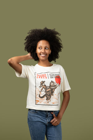 A woman wearing a boxy Tshirt with a graphic of a cat and text in front of a green background 
