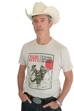 Man wearing a cowboy hat and a light t-shirt with a cat wrangler design