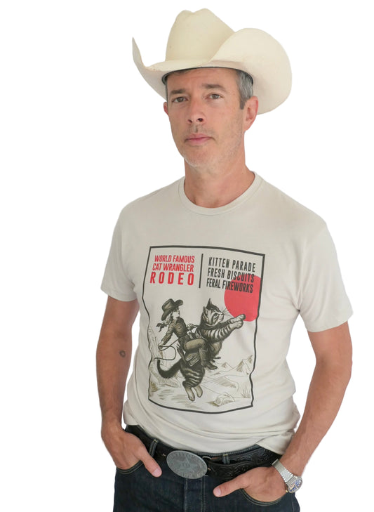 Man wearing a cowboy hat and a light t-shirt with a cat wrangler design
