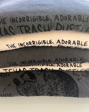 Stack of folded t-shirts with hand printed artwork of animals and funny sayings