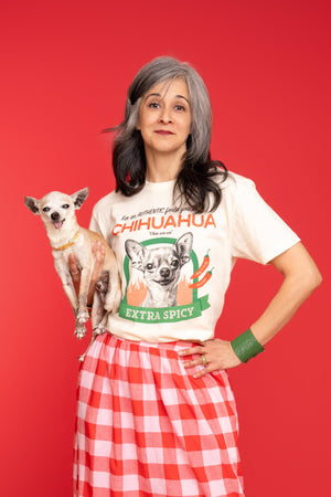 A Woman holds a chihuahua while wearing Pet Rodeo's Spicy Chihuahua t-shirt in front of a red background