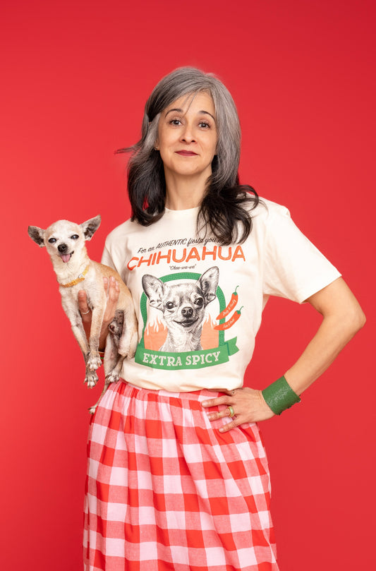 A Woman holds a chihuahua while wearing Pet Rodeo's Spicy Chihuahua t-shirt in front of a red background
