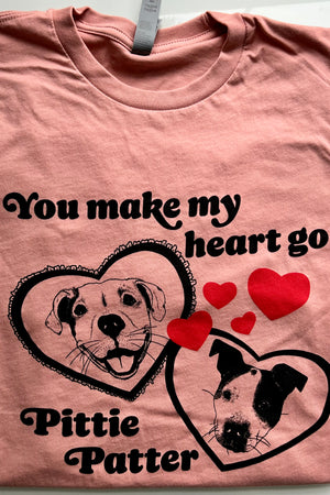 A pink tshirt with two cute hand-drawn pit bull dogs in hearts, that says "you make my heart go pittie patter"