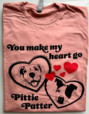 A pink tshirt with two cute hand-drawn pit bull dogs in hearts, that says "you make my heart go pittie patter"