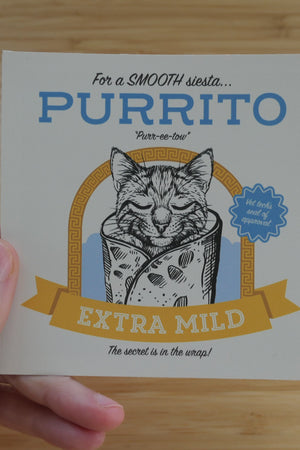 Hand holding a vinyl, 4 inch sticker that says Purrito with a cat illustration