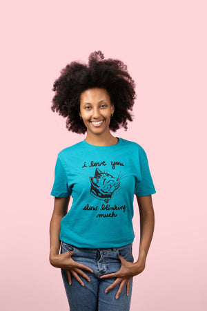 Woman wearing a teal t-shirt with a cat graphic and text on a pink background