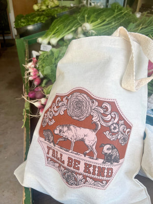 Canvas tote bag with a printed design featuring a dog, pig, and raccoon, and text 'Y'all Be Kind' at a Farm stand.